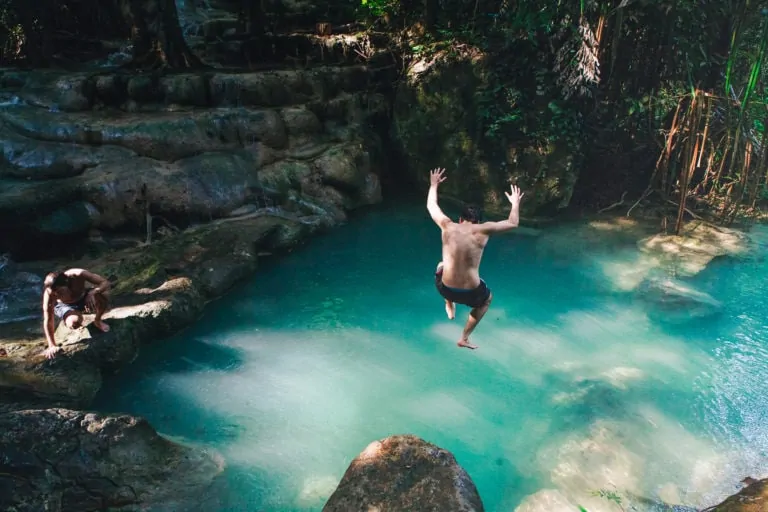 Man jumping into natural emerald pond at Erawan Waterfall